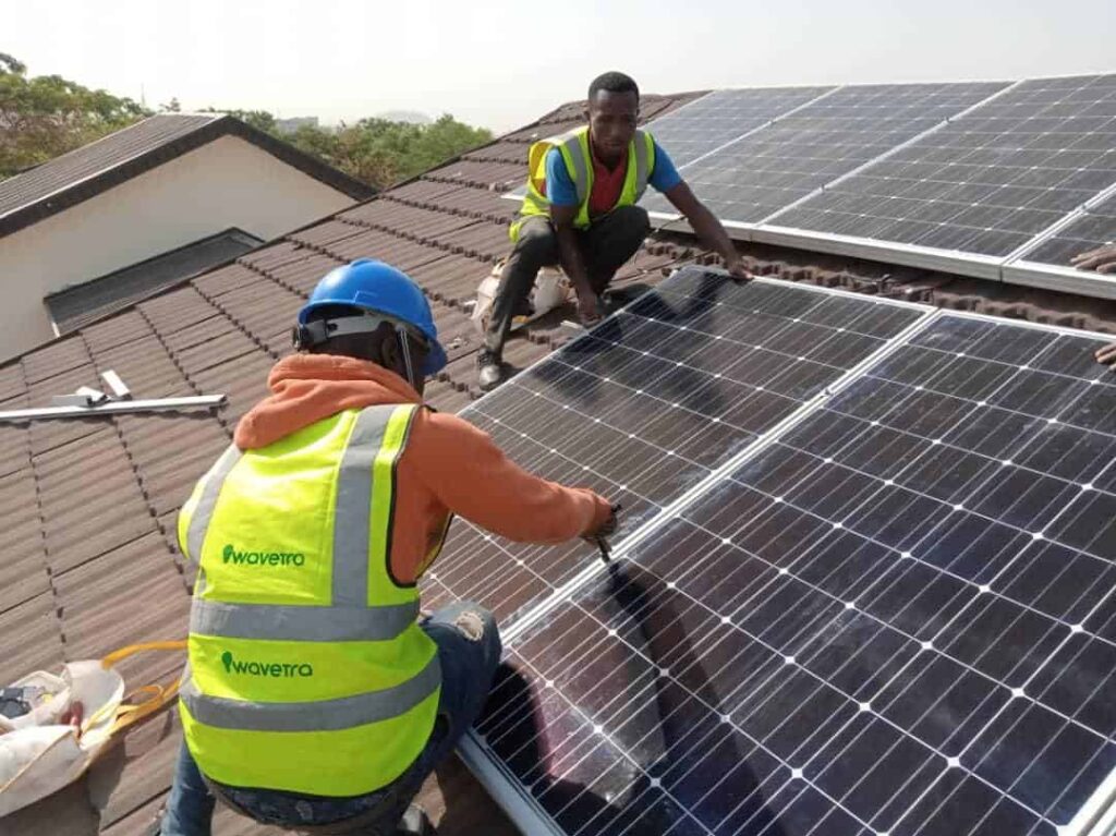 Two men installing solar panels on a roof.